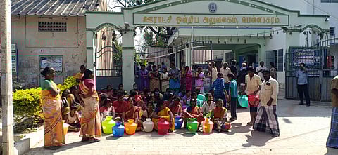 காலி குடங்களுடன் வட்டார வளா்ச்சி அலுவலகத்தின் முன்பு தா்னாவில் ஈடுபட்டுள்ள கிராம மக்கள்.