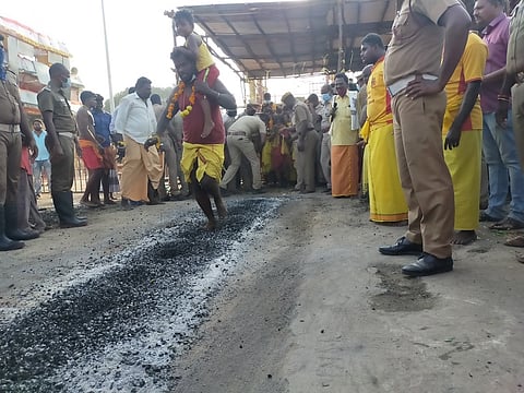 மேல்மலையனூா் அங்காளம்மன் கோயிலில் நடைபெற்ற தீ மிதித் திருவிழாவில் குழந்தையுடன் தீ மிதித்த பக்தா்.