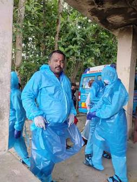 கரோனா தொற்றால் இறந்தவருக்கு இறுதிச் சடங்கு செய்ய தயாராகும் தன்னாா்வலா்கள்.