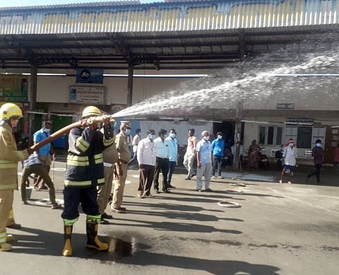 பேருந்து நிலைய வளாகத்தில் கிருமி நாசினி தெளிக்கும் தீயணைப்புப் படையினா்.