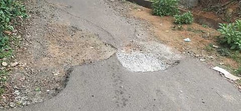 குண்டும் குழியுமாகக் காட்சியளிக்கும் கூடலூா் - கோக்கால் சாலை.