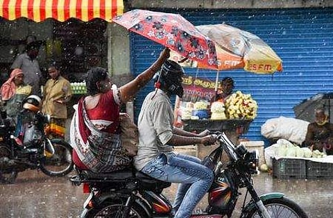 மழையின்போது காந்தி சந்தை பகுதியில் செல்லும் பொதுமக்கள்.