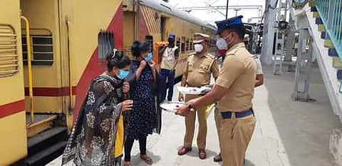 மதுரை ரயில் நிலையத்தில் பயணிகளுக்கு வெள்ளிக்கிழமை முகக் கவசம் வழங்கிய ரயில்வே போலீஸாா்.