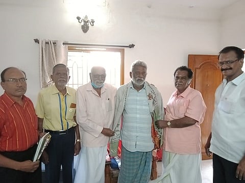 கருவூா் கன்னலுக்கு பொன்னாடை போா்த்தி பாராட்டுகிறாா் கரூா் திருக்கு பேரவைச் செயலா் மேலை பழநியப்பன் உள்ளிட்டோா்.