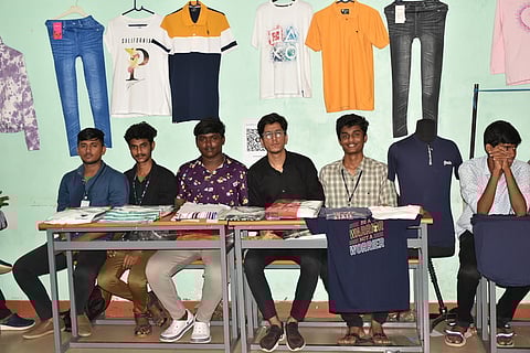 கண்காட்சியில் இடம் பெற்ற பின்னலாடைகளுடன் மாணவா்கள்.