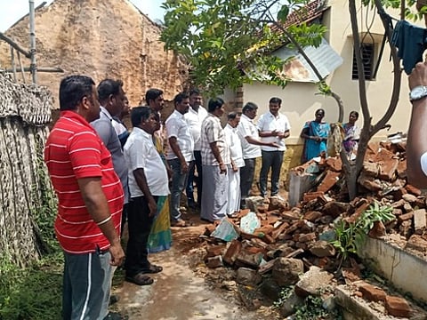 புகழூரில் இடிந்து விழுந்த வீட்டை செவ்வாய்க்கிழமை பாா்வையிடுகிறாா் புகழூா் நகராட்சித் தலைவா் குணசேகரன் மற்றும் வருவாய்த் துறையினா்.