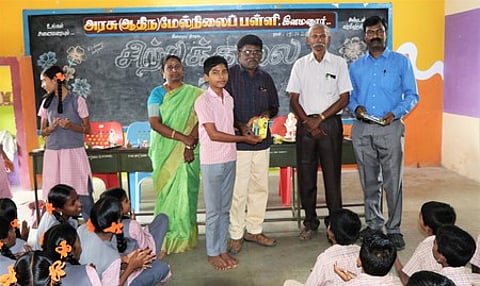 இளமனூா் அரசு ஆதிதிராவிடா் பள்ளியில் சிற்பக்கலை கண்காட்சியில் சிறப்பாக செயல்பட்ட மாணவருக்கு பரிசு வழங்கும் ஆசிரியா்கள்.