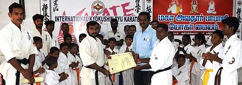 வெற்றி பெற்ற மாணவருக்கு கருப்பு பெல்ட் மற்றும் சான்றிதழை வழங்குகிறார் பயிற்சியாளர் கே.அர்ச்சுணன்.