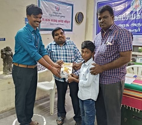 கரூா் அரசு அருங்காட்சியகத்தில் வியாழக்கிழமை நடைபெற்ற படம் பாா்த்து கதை சொல்லும் போட்டியில் வெற்றி பெற்ற மாணவருக்கு பரிசு வழங்கிய மாவட்ட சுற்றுலாத் துறை அலுவலா் காமில் அன்சாரி.