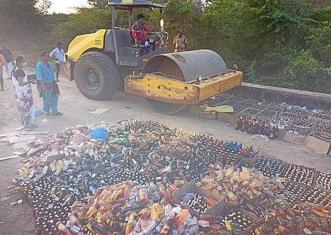 கரைப்பூண்டி ஆற்றுப் பாலத்தில் இயந்திரம் மூலம் அழிக்கப்படும் மதுப் புட்டிகள்.