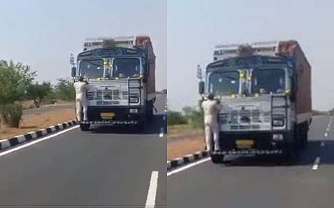 லாரியின் முகப்பில் தொங்கிய நிலையில் சுங்கச்சாவடி ஊழியர்