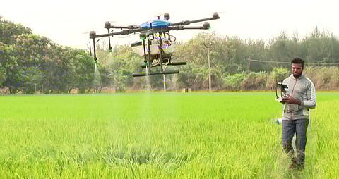 திருவள்ளூா் அருகே தலாக்காஞ்சேரியில் நெல் வயலில் பூச்சு மருந்து தெளிக்கும் பணியில் ஈடுபட்ட ஆளில்லா குட்டி விமானம்