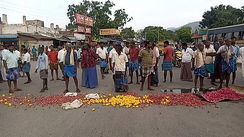 உசிலம்பட்டி பேருந்து நிலையம் முன்பாக, பூக்களை சாலையில் கொட்டி ஆர்ப்பாட்டம் மற்றும் சாலை மறியலில் ஈடுபட்ட பூ விற்பனையாளர் மற்றும் கடை உரிமையாளர்கள்.