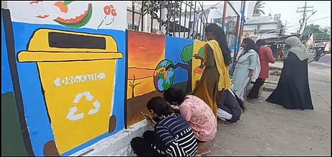 அரசு அலுவலக சுவற்றில் விழிப்புணர்வு ஓவியங்களை வரையும் கல்லூரி பெண்கள்.