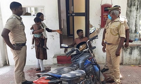 தீக்குளிக்க முயன்றவரிடம் விசாரணை நடத்தும் போலீஸாா்.