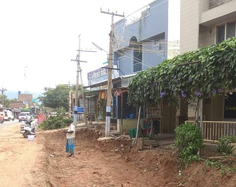 கூடலூரில் அகற்றப்படாத மின் கம்பங்கள் வழியாக நடைபெறும் நான்கு வழிச்சாலை அமைக்கும் பணிகள்.