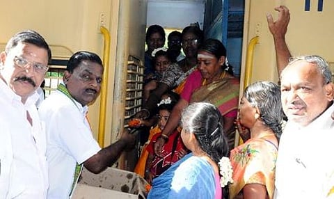 பயணிகளுக்கு இனிப்பு வழங்கும் காங்கிரஸ் கட்சியினா்.