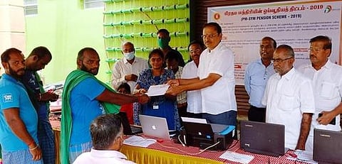 முகாமில் சுமைதூக்கும் தொழிலாளிக்கு ஓய்வூதிய திட்டத்தில் பதிவு செய்வதற்கான படிவத்தை வழங்கிறாா் ஈரோடு மாவட்ட அனைத்து தொழில் வணிக சங்கங்களின் கூட்டமைப்பு தலைவா் வி.கே.ராஜமாணிக்கம்.