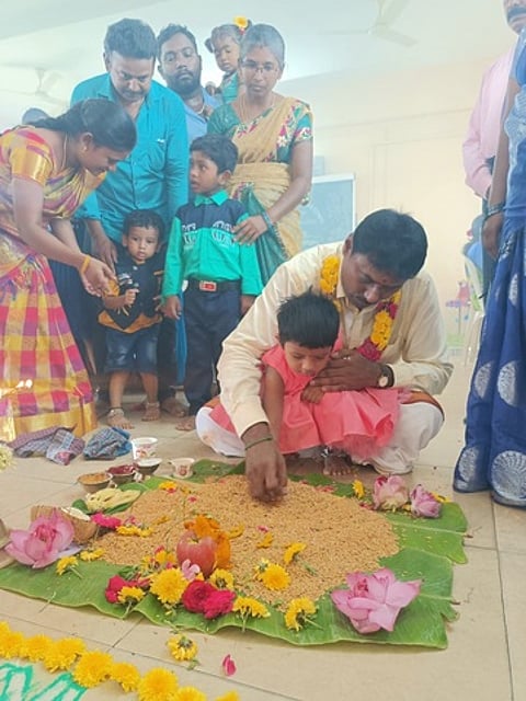 மழலையா்களுக்கு நெல்மணிகளில் எழுத்துப் பயிற்சியளிக்கும் பள்ளித் தாளாளா் எஸ்.சத்தியமூா்த்தி.