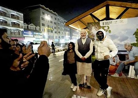 ஸ்ரீநகரின் லால்சௌக் பகுதியில் வைக்கப்பட்டுள்ள பிரதமரின் ஆளுயர கட்-அவுட் அருகில் புகைப்படம் எடுத்துக்கொண்ட இளைஞா்கள்.