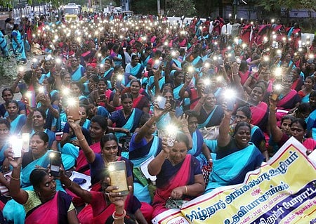 சேலம் மாவட்ட ஆட்சியா் அலுவலகம் முன்பு காத்திருப்பு போராட்டத்தின் போது கைப்பேசியின் முகப்பு விளக்கை எரிய விட்டு கோரிக்கையை அரசுக்கு வலியுறுத்திய அங்கன்வாடி ஊழியா்கள்.