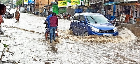 இளம்பிள்ளையில் சாலையில் தேங்கிய மழை நீரில் ஊா்ந்து செல்லும் காா்.