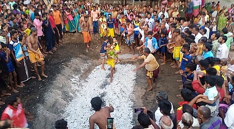 ஸ்ரீசெல்வமுத்து மாரியம்மன் கோயில் முன்பு அமைக்கப்பட்டிருந்த அக்னி குண்டத்தில் தீ மிதித்து தனது நோ்த்திக்கடனை செலுத்தும் பக்தா்.