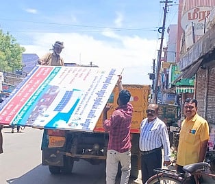 திருநெல்வேலி நகரத்தில் அனுமதியின்றி வைக்கப்பட்ட விளம்பரப் பதாகையை அப்புறப்படுத்திய மாநகராட்சிக் குழுவினா்.