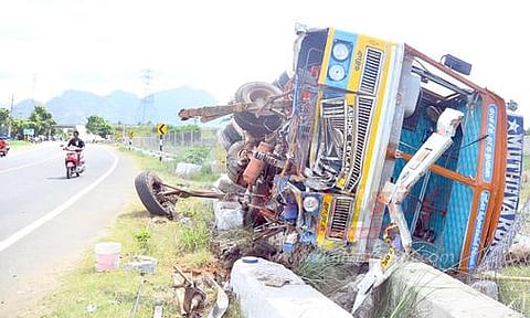 சாலையோரம் கவிழ்ந்து கிடக்கும் லாரி.