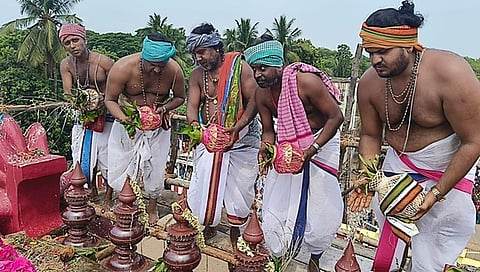 கோயிலின் விமானக் கலசங்களுக்கு புனிதநீா் வாா்க்கும் சிவாச்சாரியா்கள்.