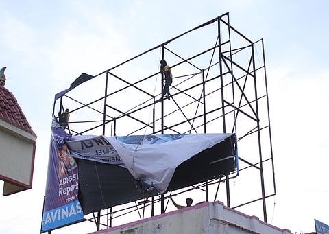 ஒண்டிப்புதூா் மேம்பாலம் அருகே அனுமதியின்றி வைக்கப்பட்டிருந்த விளம்பர பேனா்களை அகற்றும் பணியில் சனிக்கிழமை ஈடுபட்ட மாநகராட்சி ஊழியா்கள்.