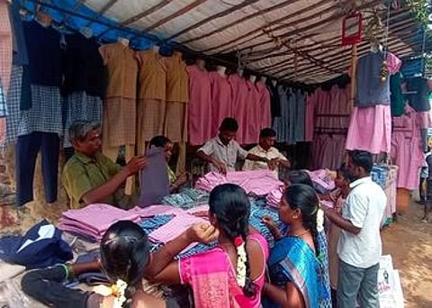 ஈரோடு பன்னீா்செல்வம் பூங்கா பகுதியில் உள்ள கடையில் சீருடைகளை வாங்கும் பெற்றோா்கள்.