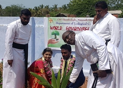 விழாவில், ஆா்வமுடன் பங்கேற்று மரக்கன்றுகளை நட்ட புதுமண தம்பதியா்.