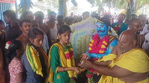 பக்தா்களுக்கு பிடிக்காசு வழங்கும் கோயில் அா்ச்சகா்.