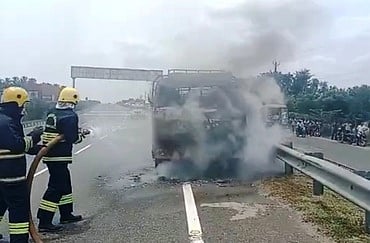 வேனில் பற்றியத் தீயை அணைக்கும் தீயணைப்புத் துறையினா்.