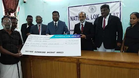 பயனாளிக்கு இழப்பீட்டுத் தொகைக்கான காசோலையை வழங்குகிறாா் மாவட்ட முதன்மை நீதிபதி அருள்முருகன்.