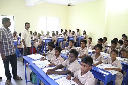 தும்பிகுளம் உயா்நிலைப் பள்ளிக்கு வழங்கப்பட்ட இருக்கைகளில் அமா்ந்துள்ள மாணவா்கள்.