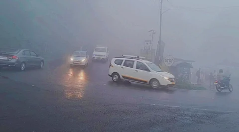 குன்னூா் அருகே மூடுபனியுடன் சாரல் மழை பெய்ததால் முகப்பு விளக்கை எரியவிட்டு இயக்கப்பட்ட வாகனங்கள்.