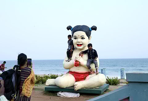 Children posing for photos with a doll statue at Beach road in Visakhapatnam. Express photo by G. Satyanarayana.
