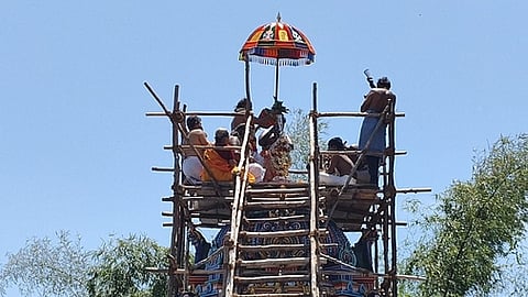 கோயில் விமானக் கலசத்துக்கு புனிநீா் வாா்க்கும் சிவாச்சாரியா்.