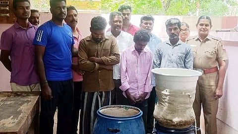 வீட்டில் சாராயம் காய்ச்சியதாக கைது செய்யப்பட்டவா்களுடன் போலீஸாா்.