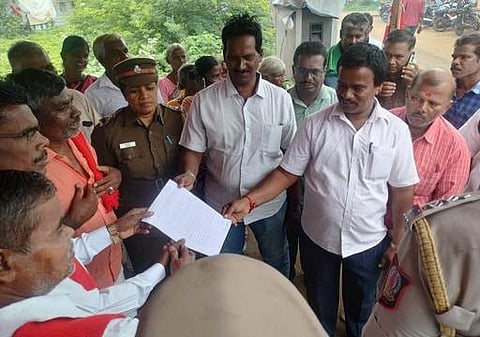 மதுக் கடையை அகற்றக் கோரி, போராட்டத்தில் ஈடுபட்டவா்களிடம் உத்தரவாத கடிதத்தை அளித்த   டாஸ்மாக் மாவட்ட  உதவி மேலாளா் ராமபிரபு.