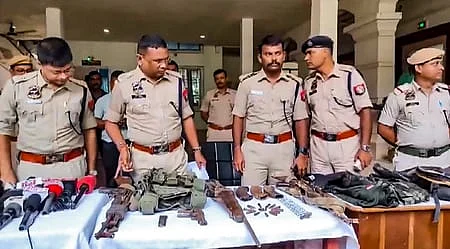அஸ்ஸாமில் தீவிரவாதிகளிடமிருந்து கைப்பற்றப்பட்ட ஆயுதங்கள், வெடிபொருள்களுடன் காவல்துறையினா்.