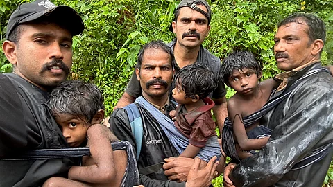 நிலச்சரிவுகளால் பாதிக்கப்பட்டுள்ள பகுதிகளிலிருந்து மீட்கப்பட்ட குழந்தைகளுடன் வனத்துறையினர்