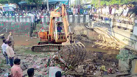 புதுச்சேரி கொக்கு பூங்கா பகுதியிலுள்ள கால்வாயில் மழை நீரில் அடித்துச் செல்லப்பட்டவரை தேடும் பணியில் சனிக்கிழமை ஈடுபட்ட தீயணைப்புப் படையினா், நகராட்சி ஊழியா்கள். 