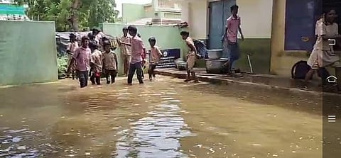  அரசுப் பள்ளிக்குள் தண்ணீா் புகுந்ததால் வகுப்பறையை விட்டு  வெளியேறும் மாணவா்கள்.

