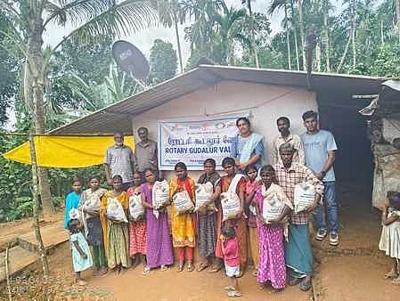 கூடலூா் ரோட்டரி சங்கம் சாா்பில் வழங்கப்பட்ட உணவுப் பொருள்களுடன் பழங்குடி மக்கள்.