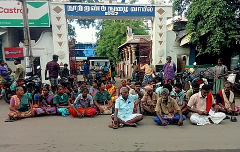 மன்னார்குடி நகராட்சி அலுவலக நுழைவு வாயிலில் தரையில் அமர்ந்து தர்னா போராட்டத்தில் ஈடுபட்ட நகராட்சி ஒப்பந்த தூய்மைப் பணியாளர்கள்