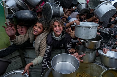 காஸாவில் உணவு வழங்குமிடத்தில் பாத்திரங்களை ஏந்தி நிற்கும் சிறார்கள். Photo; AP 
