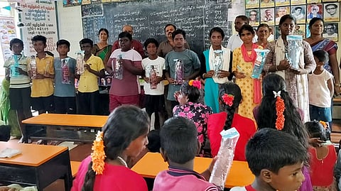   மாணவா்களுக்கு நலத்திட்ட உதவிகளை வழங்கிய முன்னாள் பள்ளித் தலைமையாசிரியா் என்.கே.ராமலிங்கம் குடும்பத்தினா். 